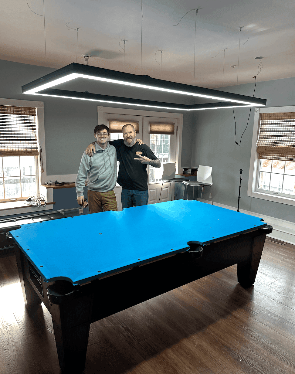 Master Billiards team with a freshly recovered table under an LED light fixture