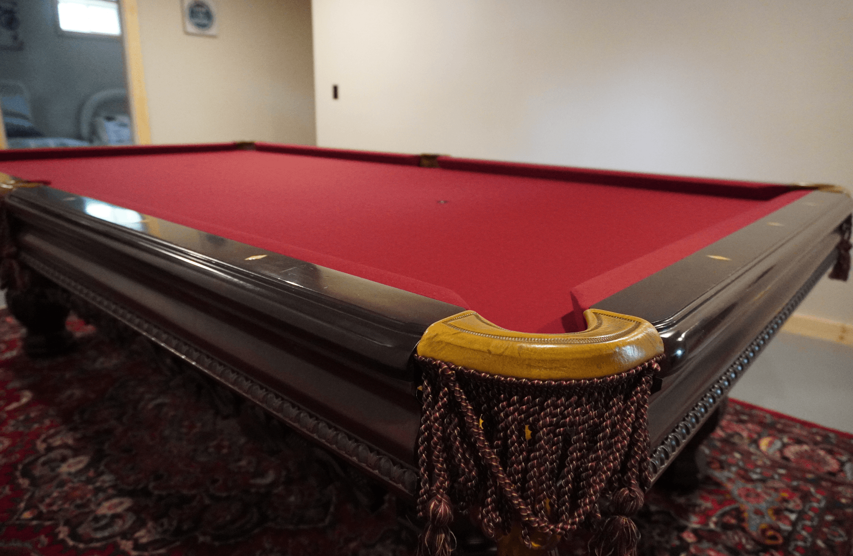 Angled view of an antique table with burgundy cloth and tasseled drop pockets