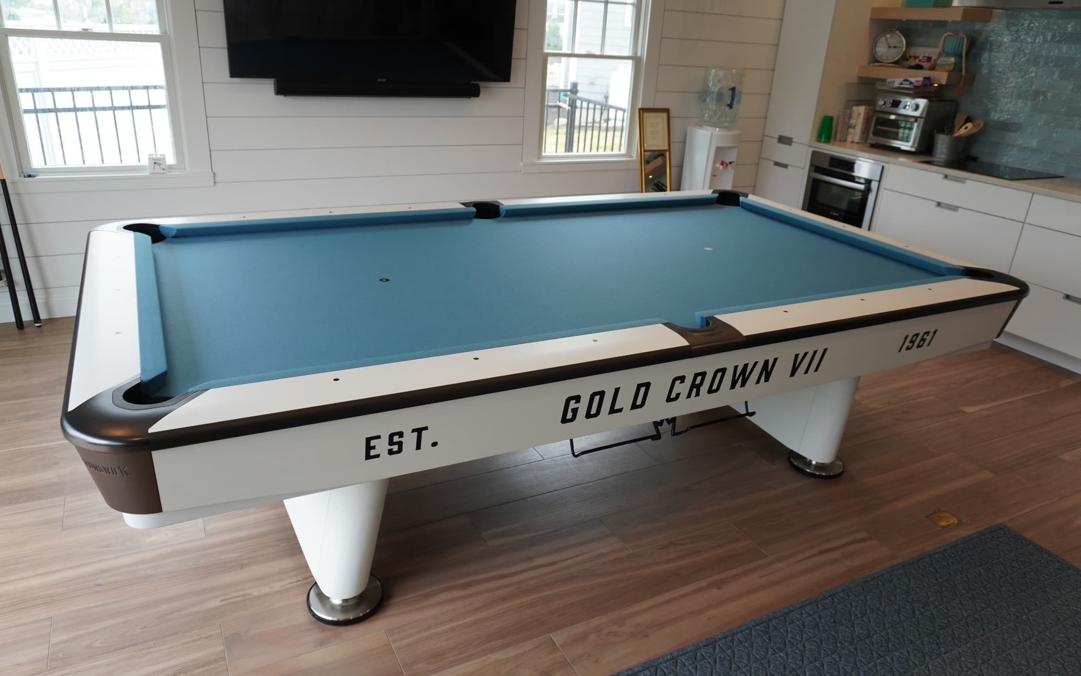 Angled view of a Brunswick Gold Crown VII table with blue cloth beside a white kitchen