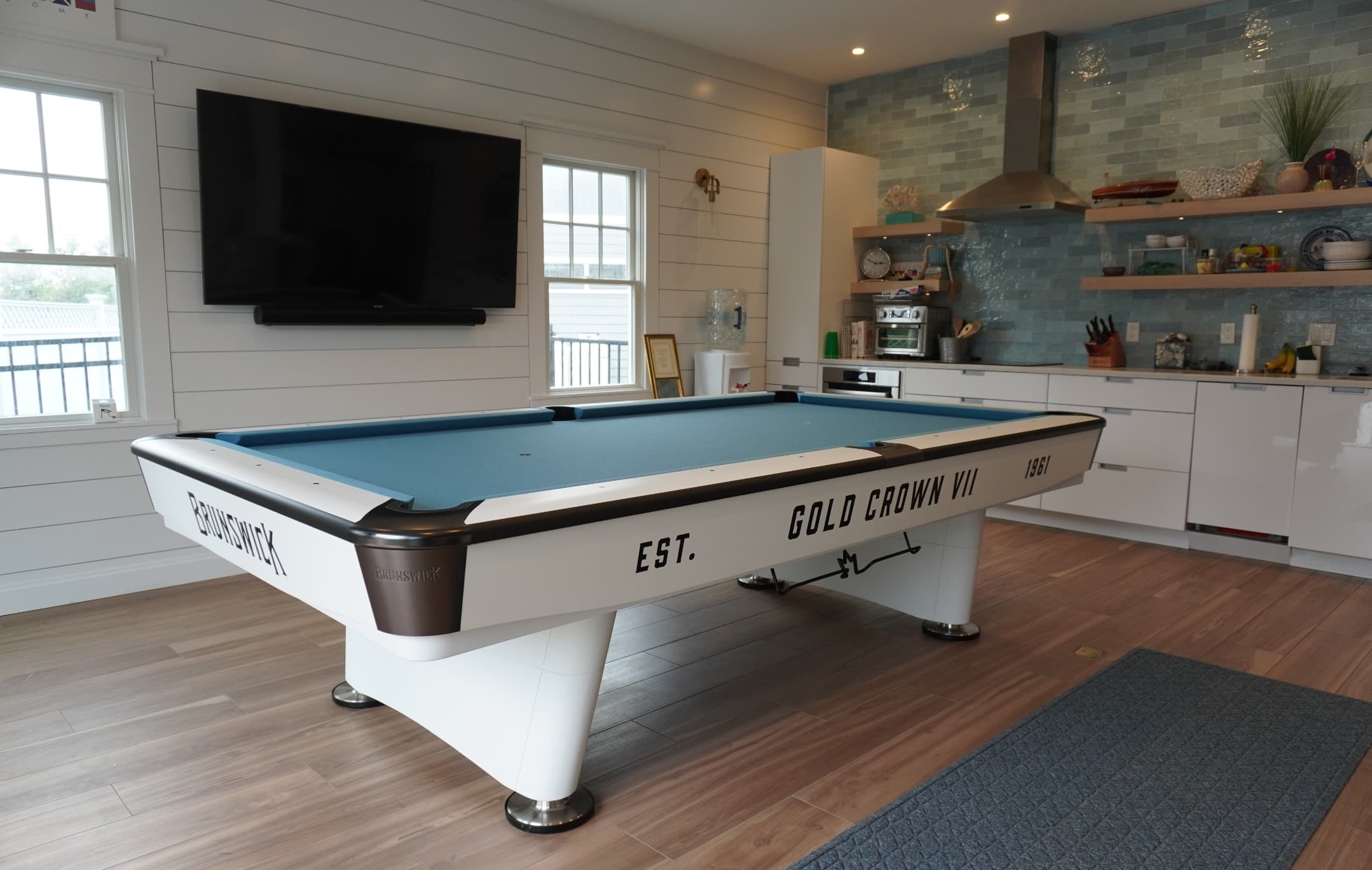 Brunswick Gold Crown VII pool table with light blue cloth in a bright coastal game room
