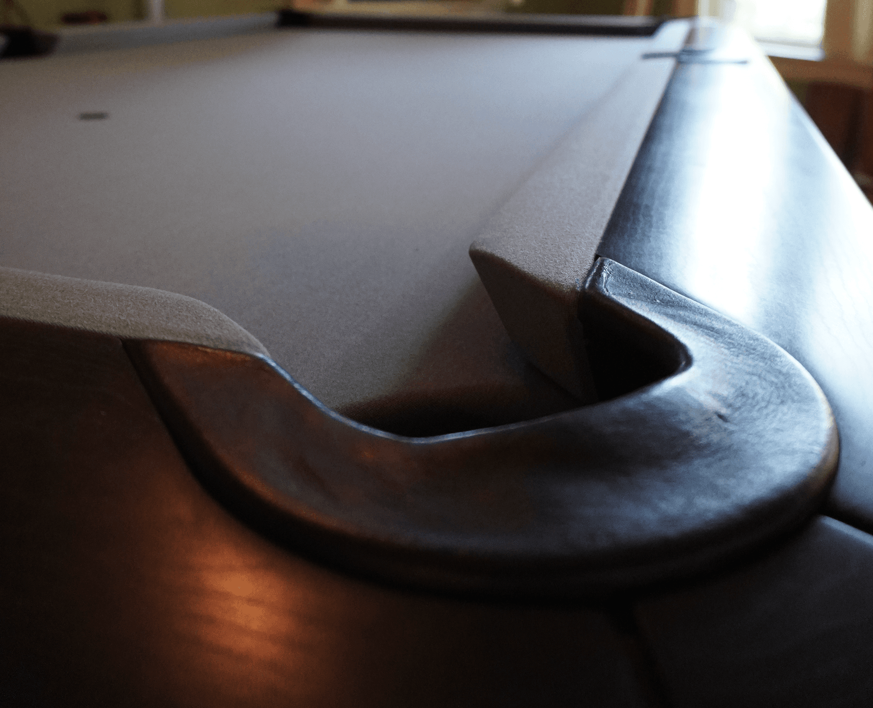 Macro view of a pool table rail and pocket with new gray cloth
