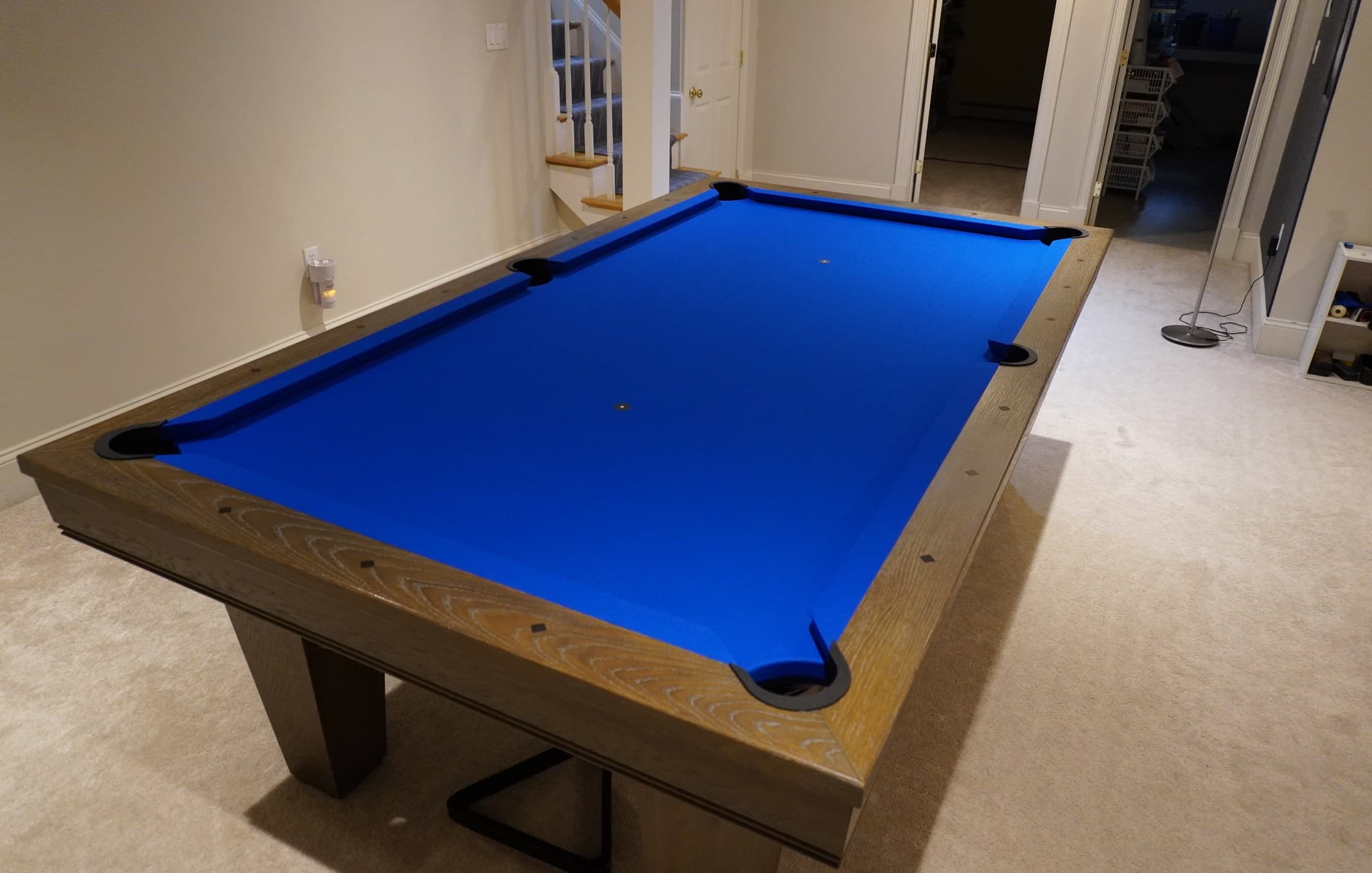 Weathered-oak table with royal blue cloth set up in a finished basement