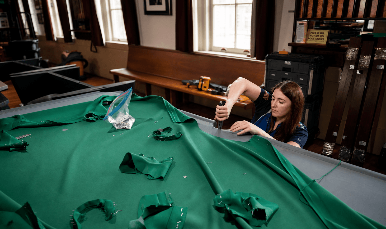 Technician recovering a pool table with new green felt