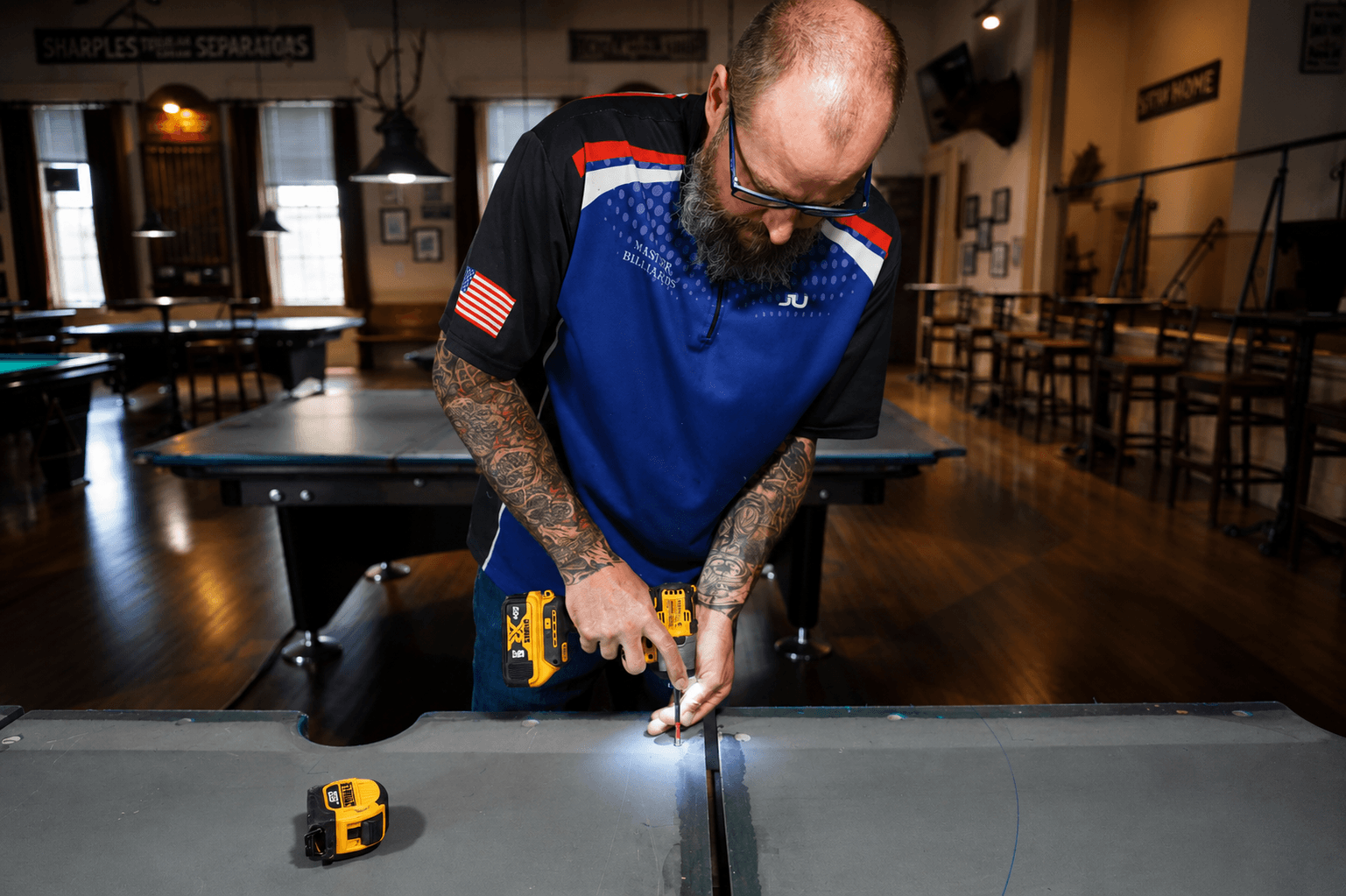 Master Billiards technician drilling into a pool table slate during installation