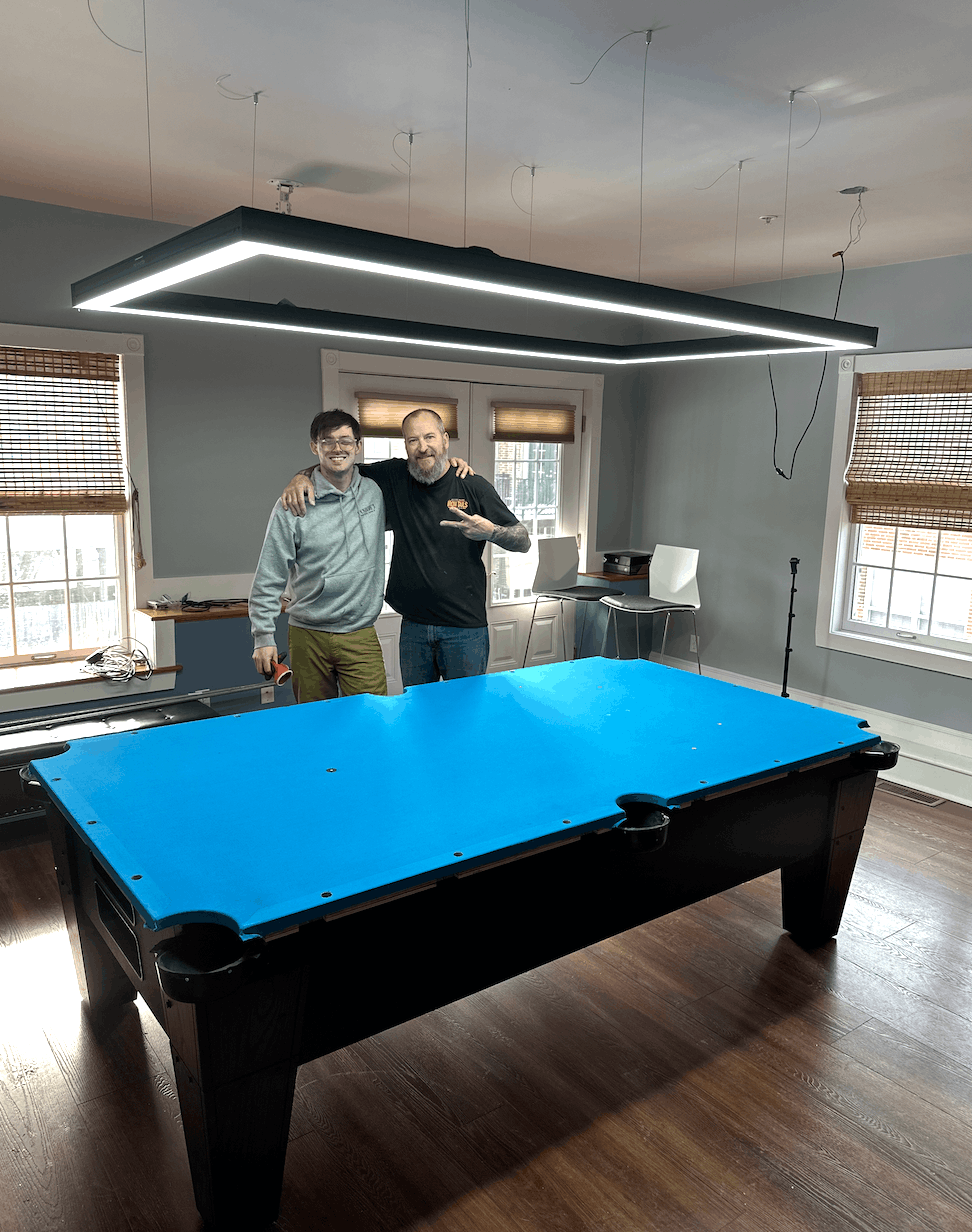 Master Billiards team with a freshly recovered table under an LED light fixture