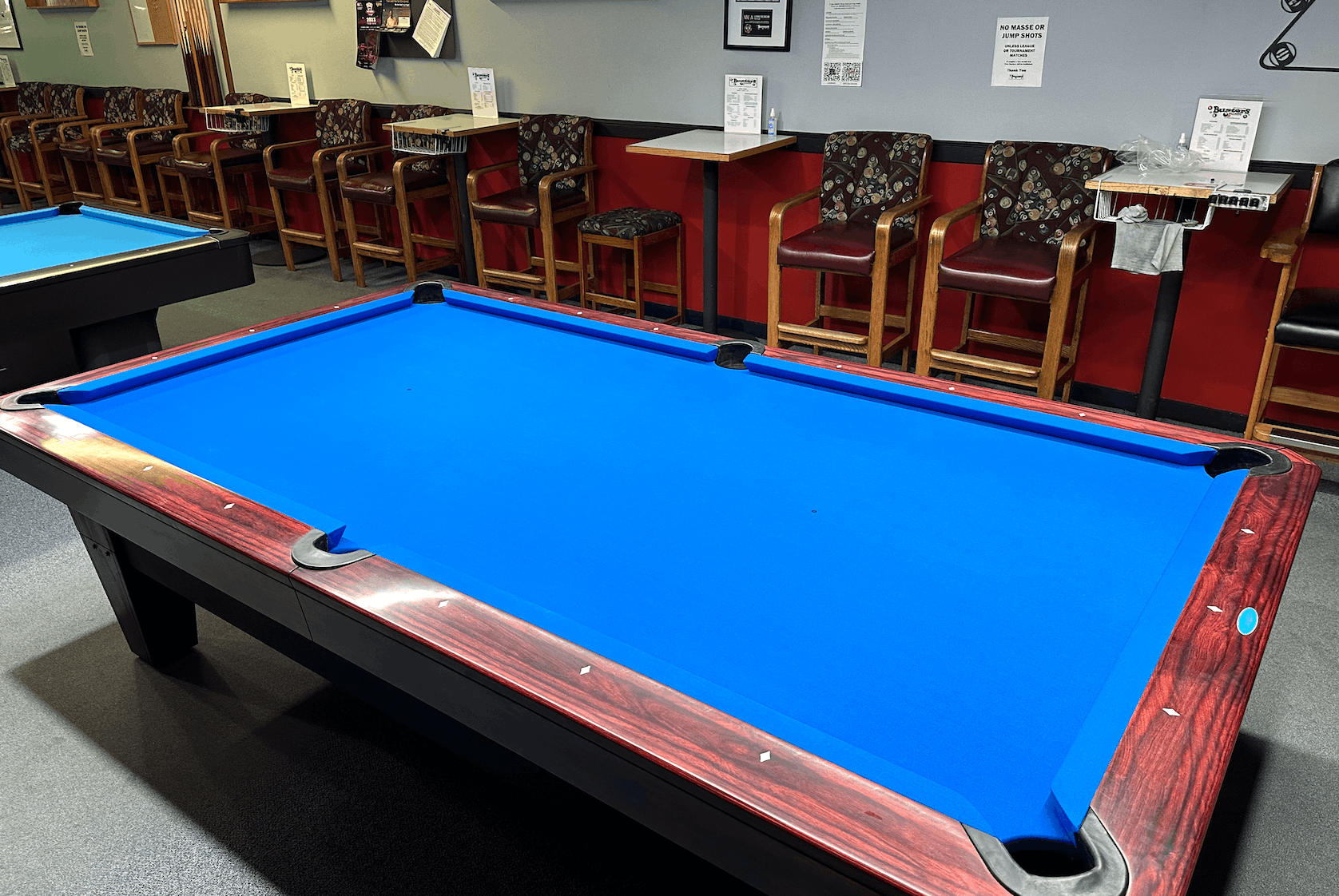 Blue-felt table with wooden bar stools against a red wall