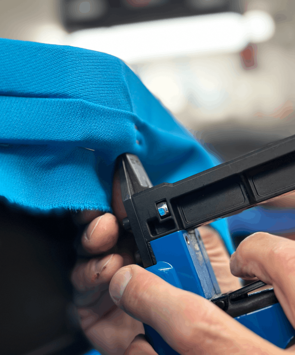 Stapling new blue cloth tight to a rail with a pneumatic stapler