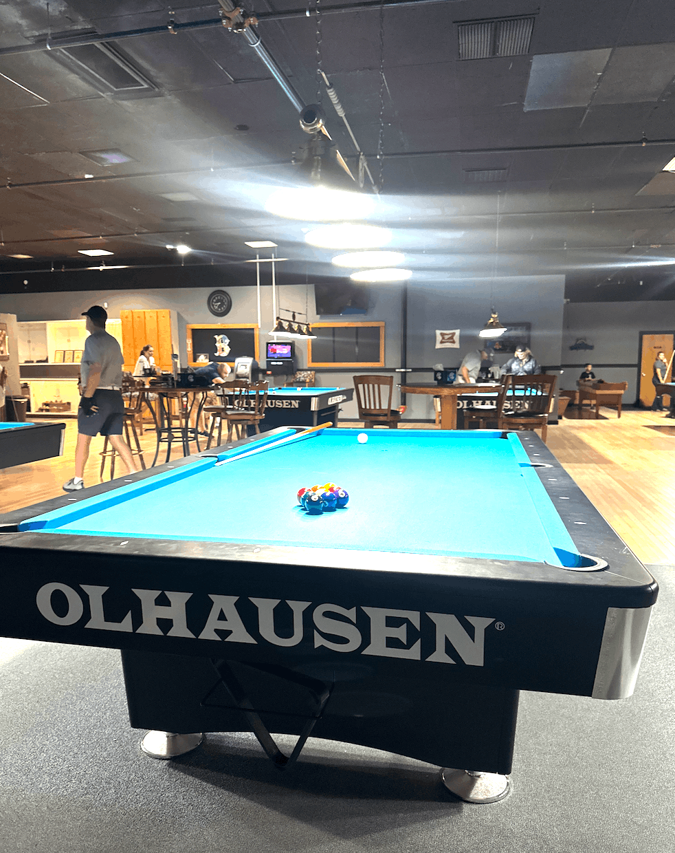 Olhausen table with blue cloth in a busy pool hall